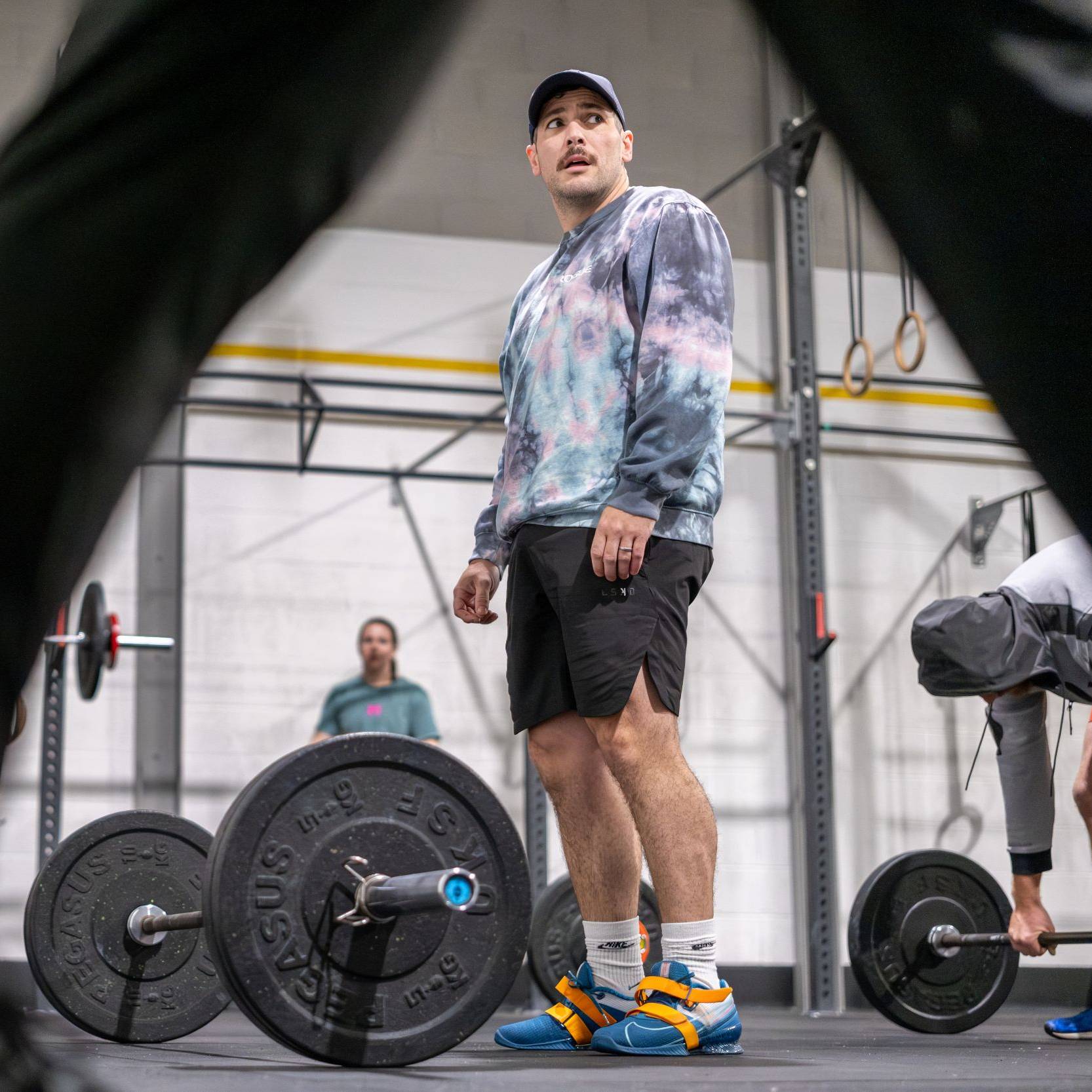 A man standing over weights at a gym
