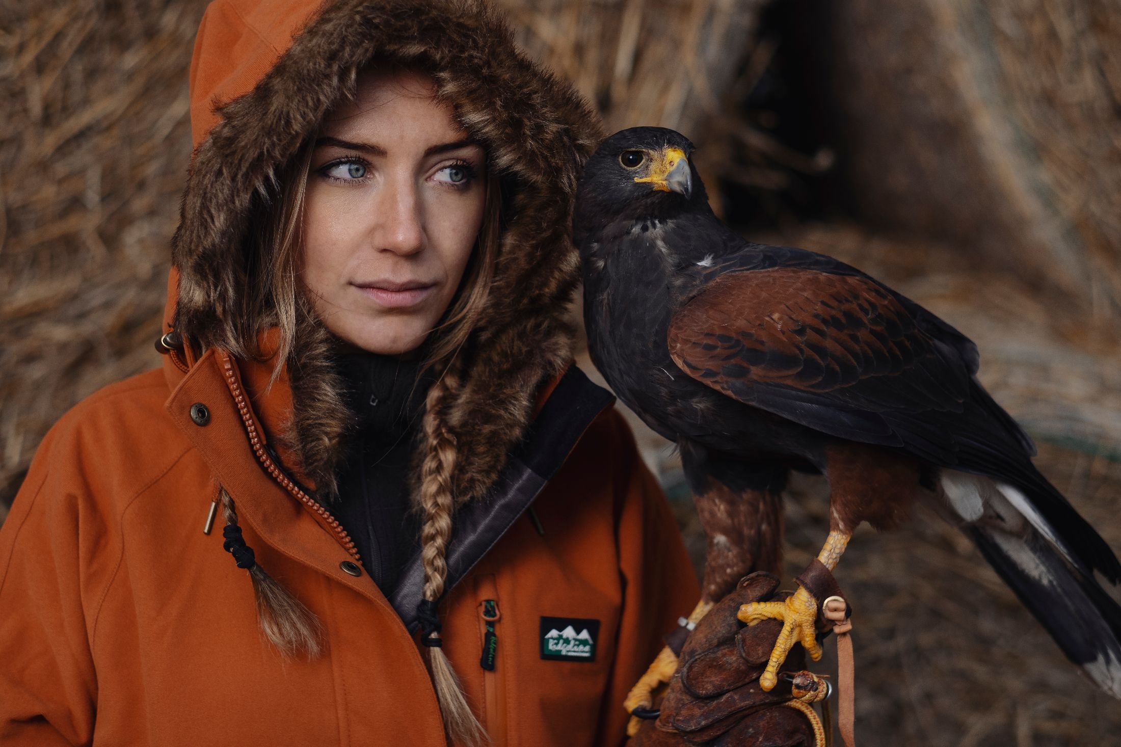 A woman in hiking gear holding a bird of prey